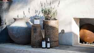 Soy candle in mason jar, reed diffuser with amber bottle, room spray with amber bottles surrounded by lavender flowers